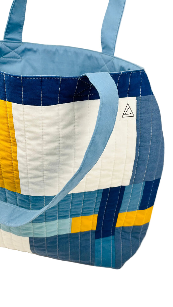Quilted tote bag with blue, yellow, and white pattern on a light background