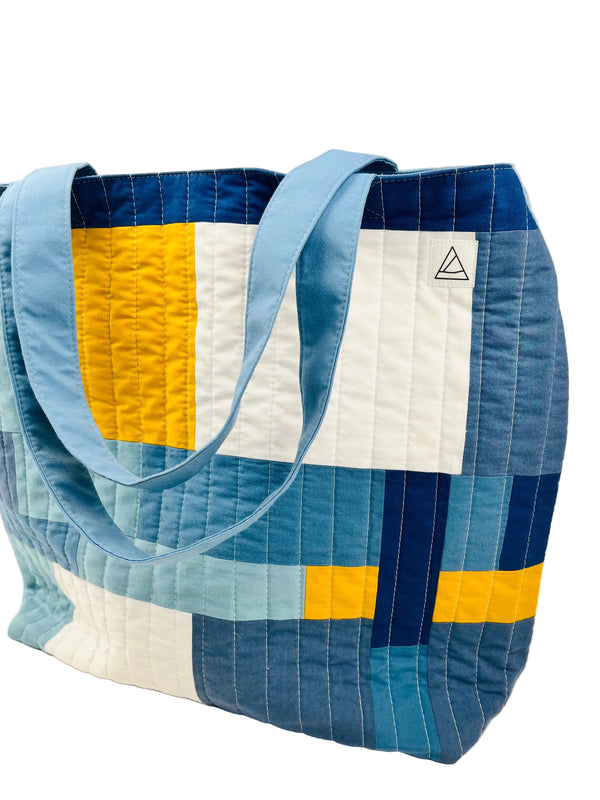 Quilted tote bag with blue, yellow, and white pattern on a light background