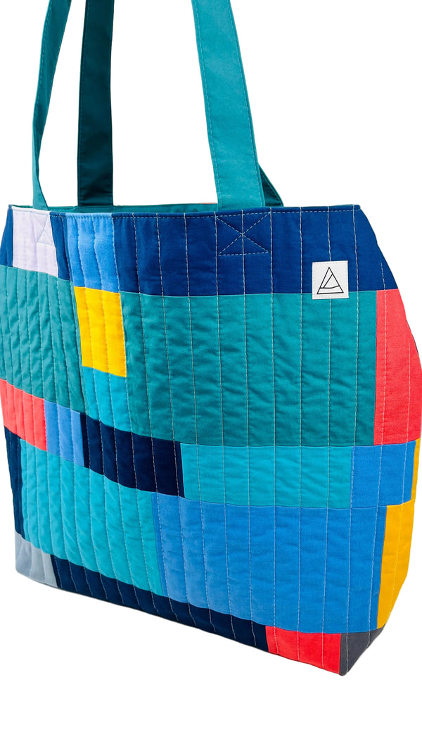 Colorful quilted tote bag with geometric pattern on a white background