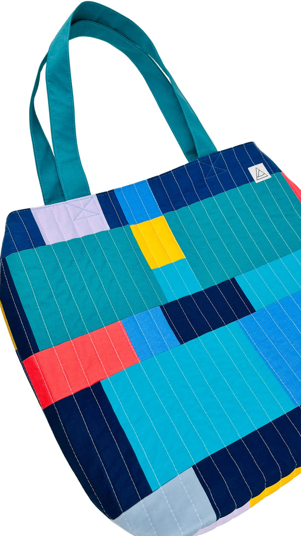 Colorful quilted tote bag with geometric pattern on a white background