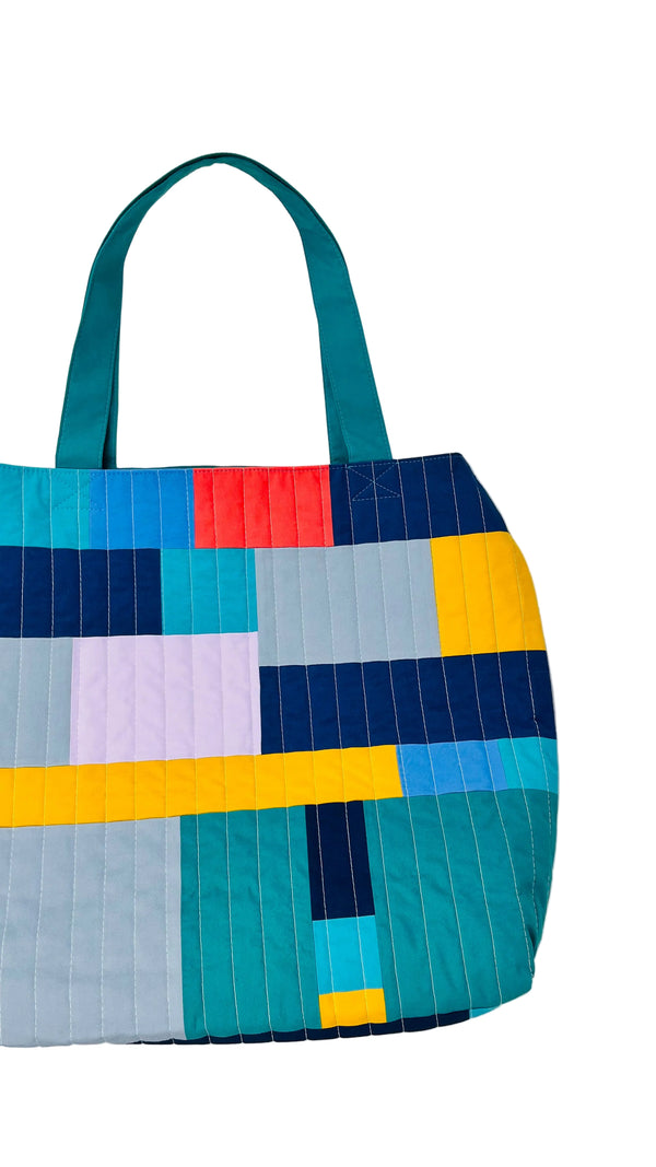 Colorful quilted tote bag with geometric pattern on a white background
