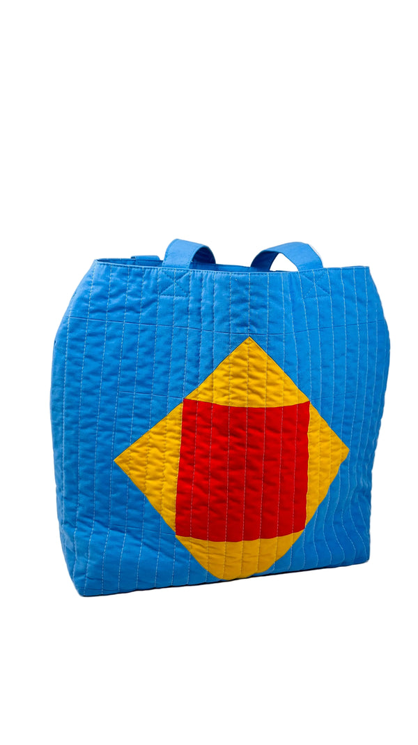 Blue quilted bag with red and yellow diamond pattern on a white background