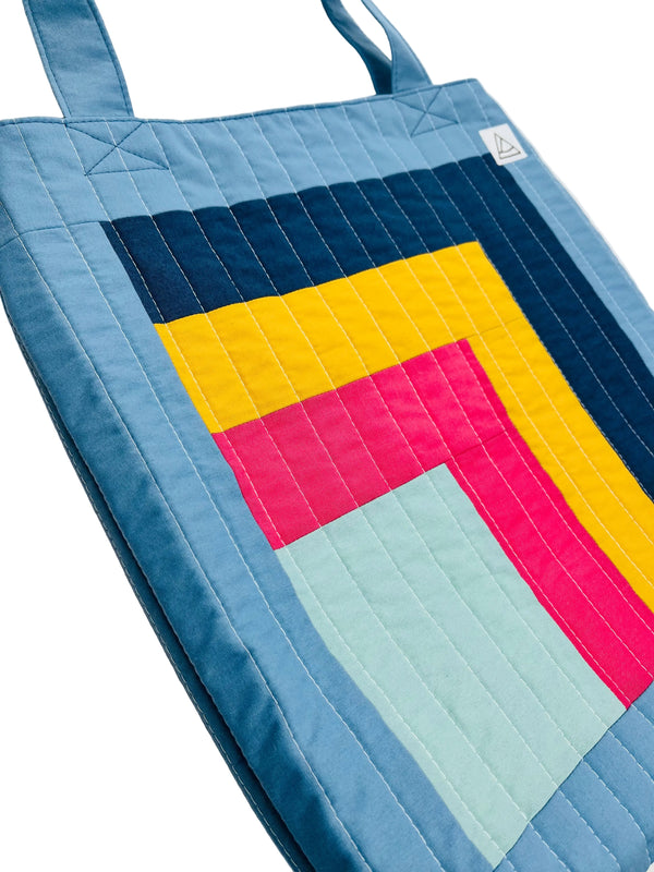 Colorful quilted tote bag with geometric pattern on a white background