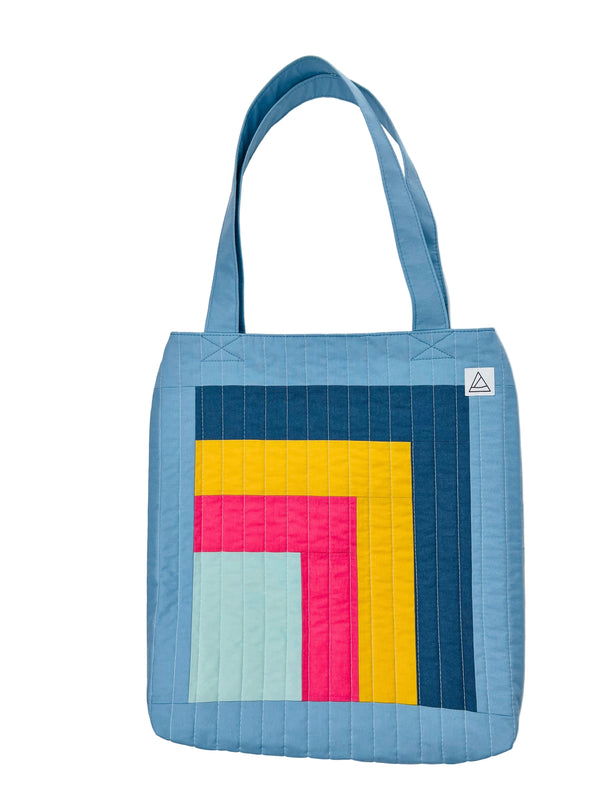 Colorful quilted tote bag with geometric pattern on a white background