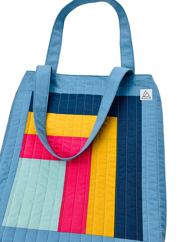 Colorful quilted tote bag with a geometric pattern on a white background