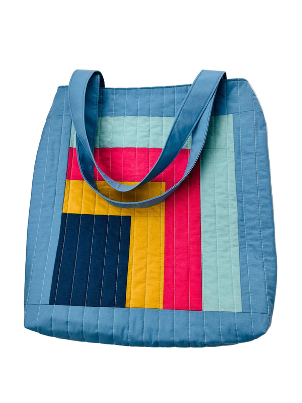 Colorful quilted tote bag with geometric pattern on a white background