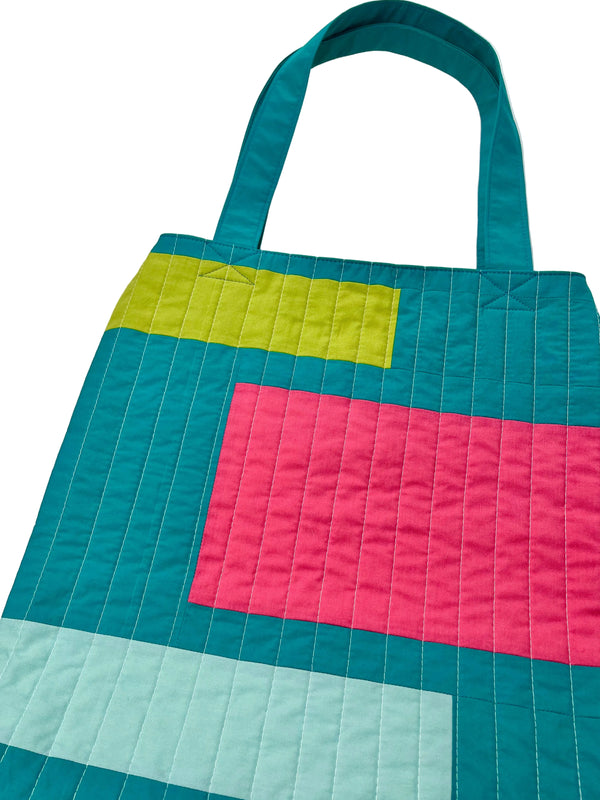 Colorful quilted tote bag with geometric pattern on a white background