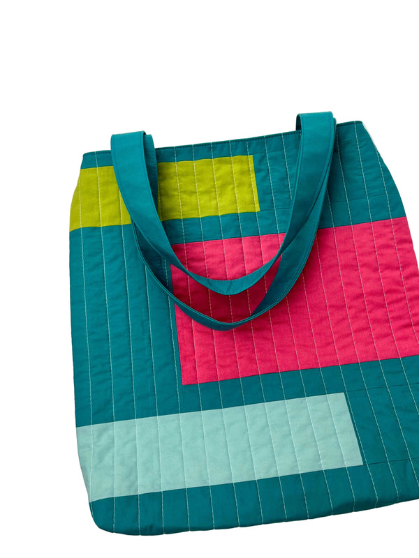 Colorful quilted tote bag with geometric pattern on a white background