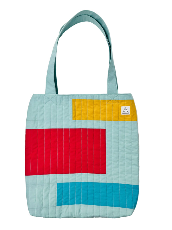 Colorful quilted tote bag with geometric pattern on a white background