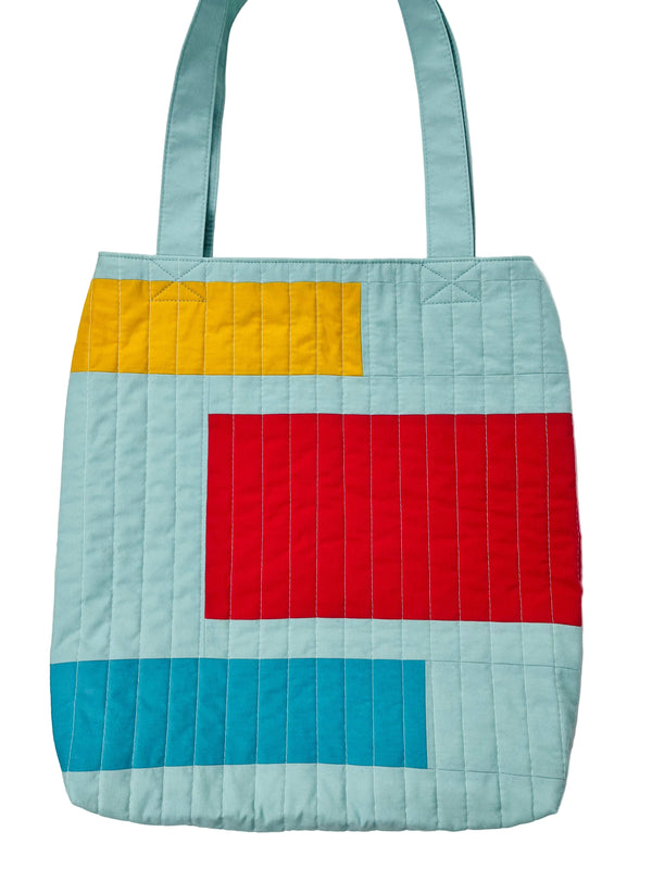Colorful quilted tote bag with geometric pattern on a white background