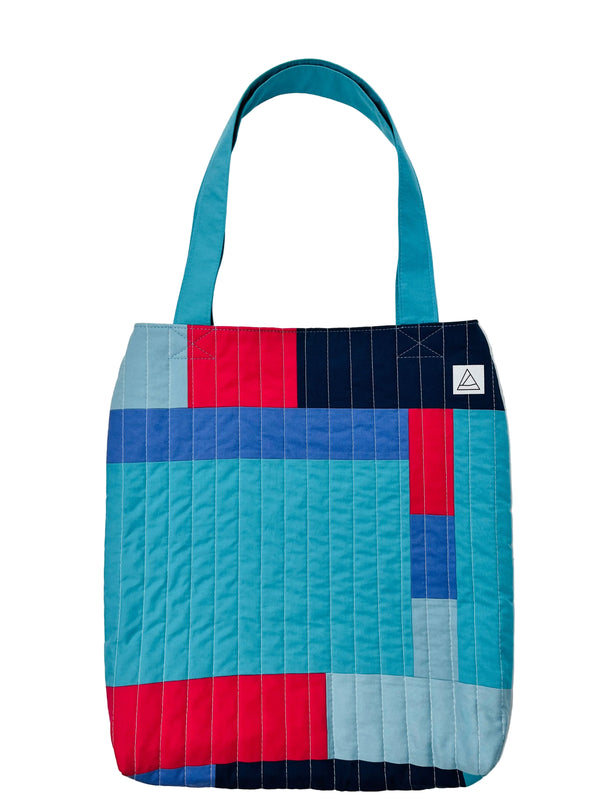 Colorful quilted tote bag with geometric pattern on a white background