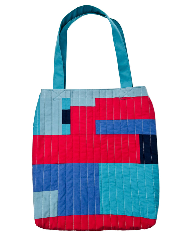 Tote bag with a geometric pattern in red, blue, and gray on a white background