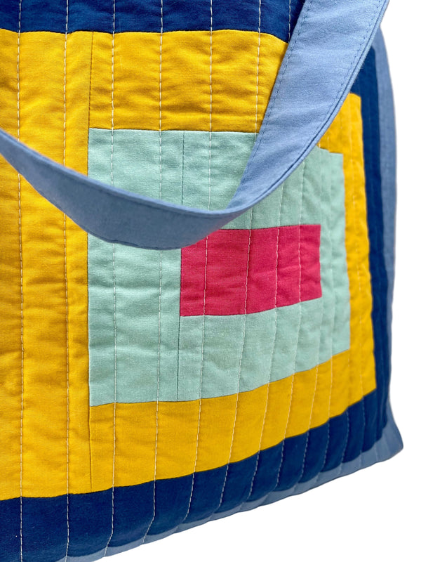 Colourful quilted bag with geometric patterns on a white background