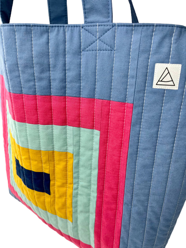 Colourful quilted tote bag with geometric patterns on a white background