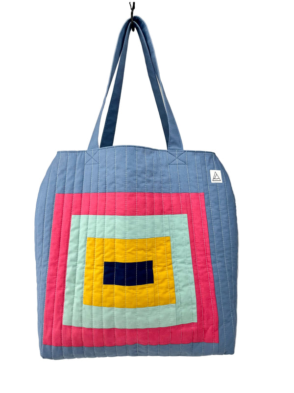 Quilted tote bag with colorful square pattern on a plain background
