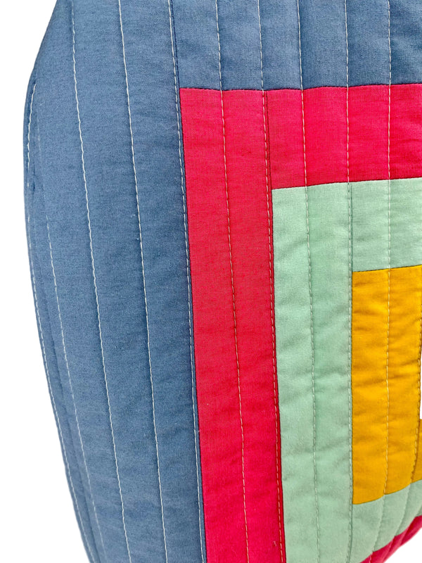 Colourful quilted bag with geometric pattern on a plain background