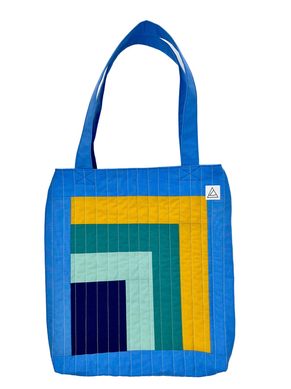 Colorful quilted tote bag with geometric pattern on a white background
