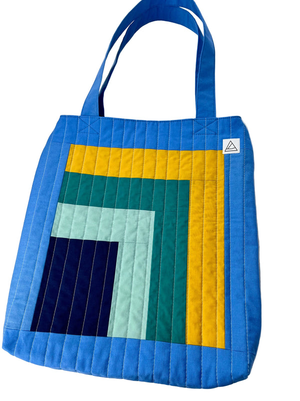 Colorful quilted tote bag with geometric pattern on a white background
