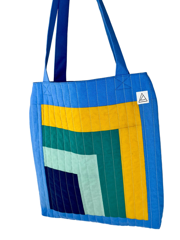 Colorful quilted tote bag with geometric pattern on a white background