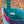 Close-up of a colourful bag with a visible brand label on a textured ground.