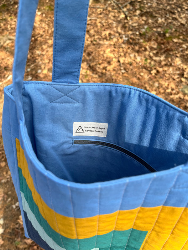 Blue quilted bag with colourful stripes on a natural background