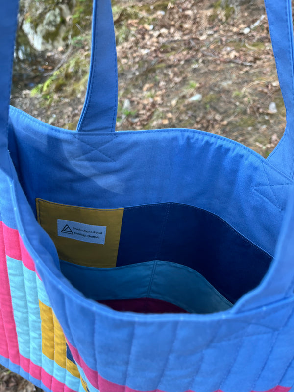Close-up of a blue bag with a colorful interior, outdoors.