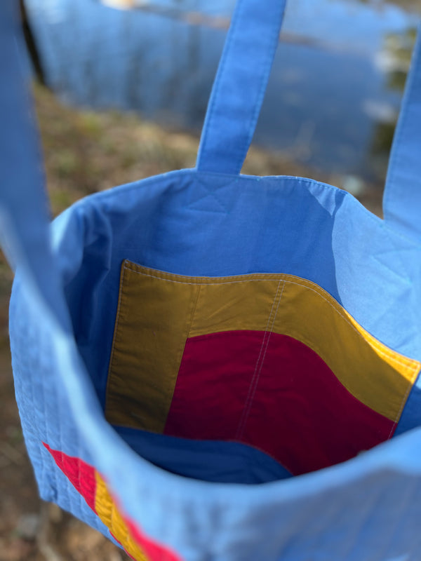 Close-up of a blue bag with colorful interior lining, blurred background